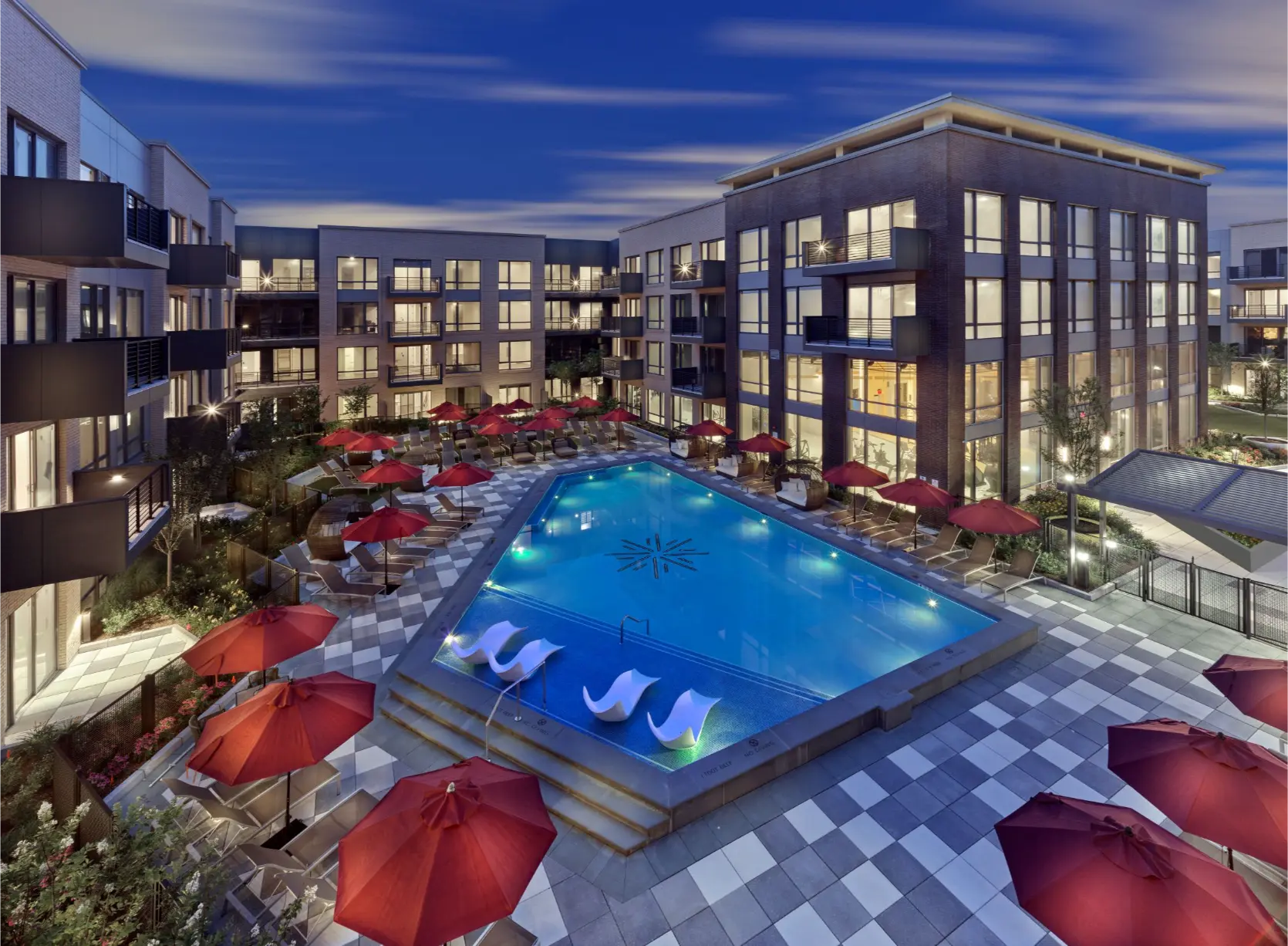 Lit outdoor pool in a modern apartment courtyard at night